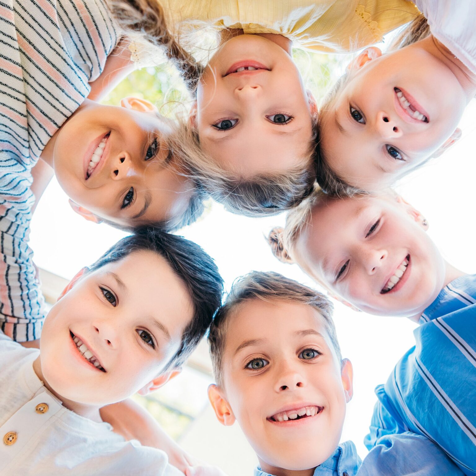 bottom biew of group of adorable schoolchildren standing in circle and looking at camera